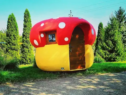 Bright red and yellow rounded house with white spots