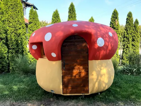 Round toadstool house with a red spotted cap roof